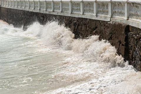 Wave breaking against a stone wall Stock Photos