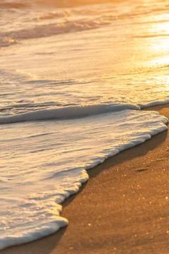 Wave breaking on the beach forming white foam Stock Photos