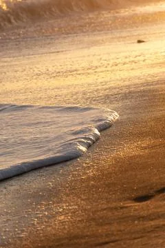 Wave breaking on the beach forming white foam Stock Photos