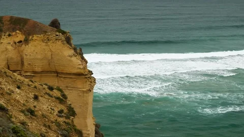 Wave breaking behind orange cliff Stock Footage 274345535