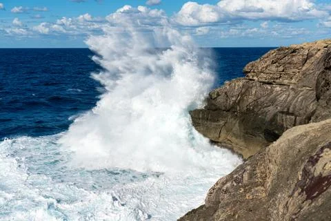Wave breaking on a cliff Stock Photos