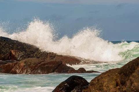 Wave Breaking on Dark Rocks Stock Photos