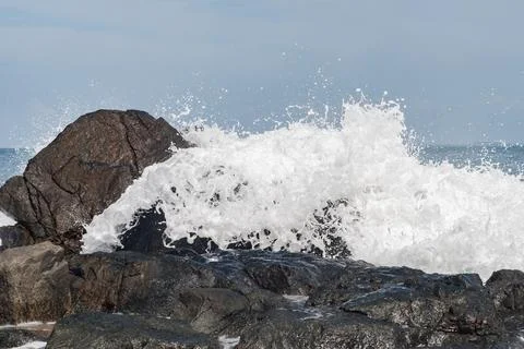 Wave Breaking on Dark Rocks Stock Photos