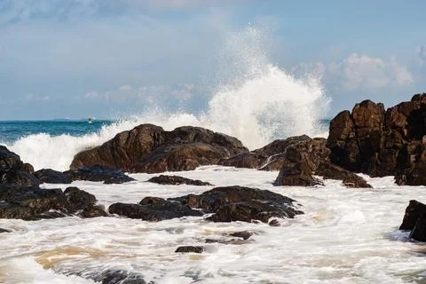 Wave Breaking on Dark Rocks Stock Photos