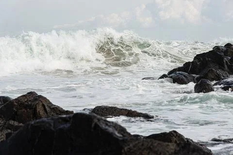 Wave Breaking on Dark Rocks Stock Photos