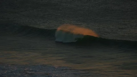 Wave breaking with orange light glow on the water Vídeo Stock 261705318