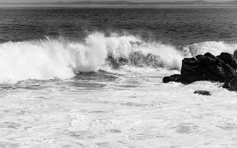 Wave breaking on rocks at the beach Stock Photos