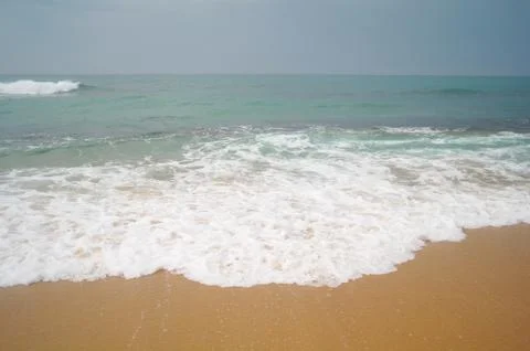 Wave breaking on a sandy beach Stock Photos