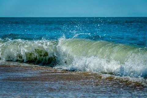 Wave breaking on a sandy shoreline Stock Photos