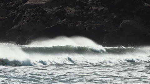Wave breaking with wind spray along a dark rocky shore in Iceland Stock-Footage 348026248