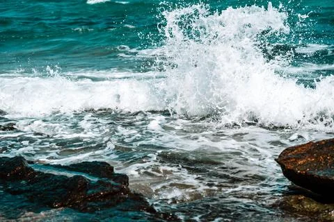 The wave breaks on the rocks, forming white foam. Tropical island, travel and Foto stock