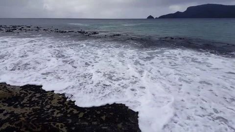 A wave of bubbles slamming the beach at Adventure bay Bruny Island Tasmania Stock Footage 81804096