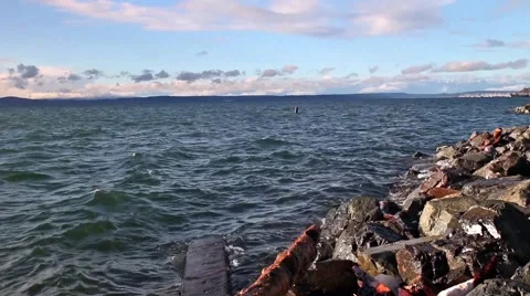 Wave crash over rocks and drift wood during sunset Washington Sound Still  Video stock 58628852