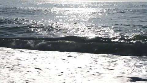 Wave crashes covers and drags pebbles on the beach on a summer morning Stock Footage 84015040