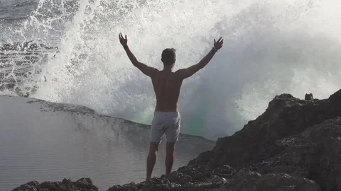 Wave Crashes in Front of Man in Slow Motion Stock Footage 106785187