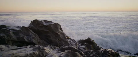 Wave crashes over rocks in slow-mo at dusk Stock Footage 136448429