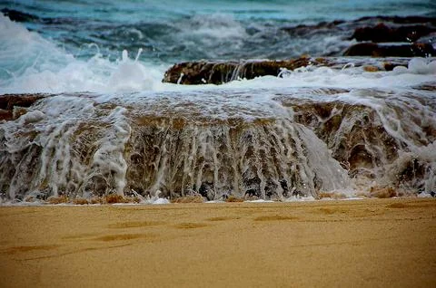 Wave flowing over a rock Stock Photos