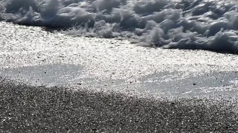 Wave with foam covers and drags pebbles on the beach Stock Footage 84013146