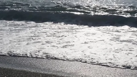 Wave with foam covers and drags pebbles on the beach Stock Footage 84014970