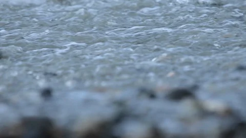 A wave of foam licks the shore of the pebbly sea shore. Stock Footage 122907813