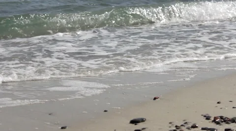 Wave Foam on a Sandy Beach Foamy waves roll over the sandy texture of the beach. Stock Footage 44250041