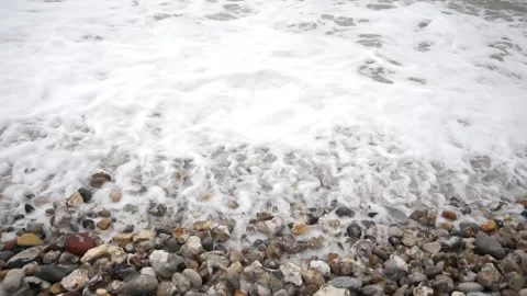A wave from the French Atlantic slow motion rolls onto the pebble beach Stock Footage 345572659
