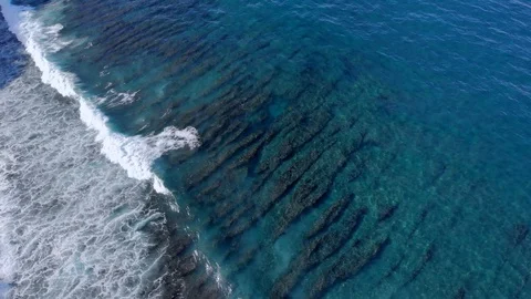 A wave hits an ocean reef off the coast of Bali video from a drone.  Stock Footage 127590389
