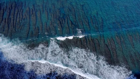A wave hits an ocean reef off the coast of Bali video from a drone.  Stock Footage 127590470