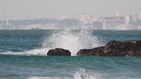 The wave is hitting the reef. In the background the tourist resort of Caparica Stock Footage 231477773