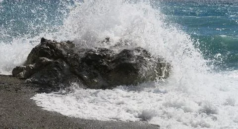 Wave hitting a rock on the beach Stock Photos