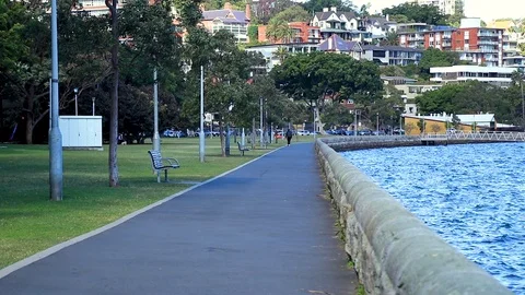 Wave lapping the shore line adjacent a footpath line with trees and lamp Stock Footage 118062812