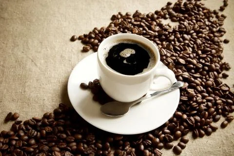Wave made of coffee beans with cup of coffee with foam on linen,flax Stock Photos