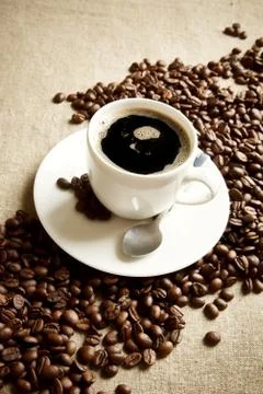 Wave made of coffee beans with cup of coffee with foam on linen,flax Stock Photos