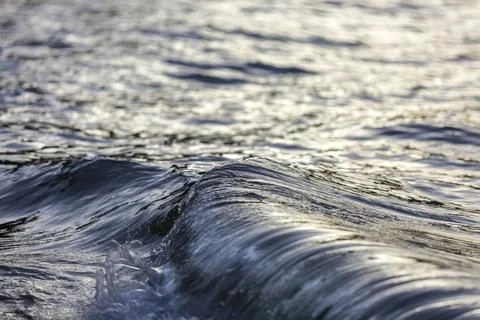 A wave in the ocean with the sun shining on it Stock Photos