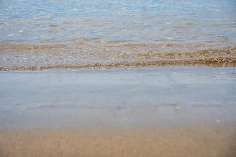 Wave reaching a calm sandy beach. Front view close-up. Ground level view. Stock Photos