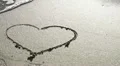 A wave removes a heart drawn in the sand HD Footage