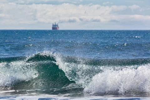 The wave rolls ashore on the background of the ship Stock Photos