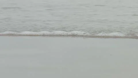 A wave rolls onto the sandy shore Stock Footage 288986281