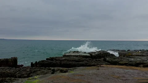 A wave is running through the many cracks of a worn out rocky cape Stock Footage 234954919