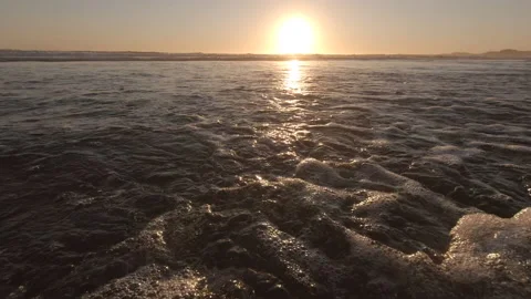 Wave rushing over sandy beach towards camera at sunset. Low angle close up. Stock Footage 135422485
