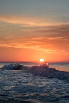 Wave splash on the background of a beautiful sunset or dawn. Stock Photos