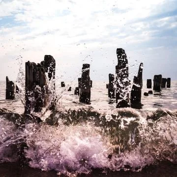 The wave splashes on the pier logs on the beach Stock Photos