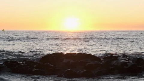 Wave splashes in slow motion against rocks on beach, at sunset, Stock Footage 115758858