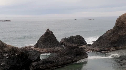 A wave splashing between two sea stacks on the pacific coast. Video stock 107300181