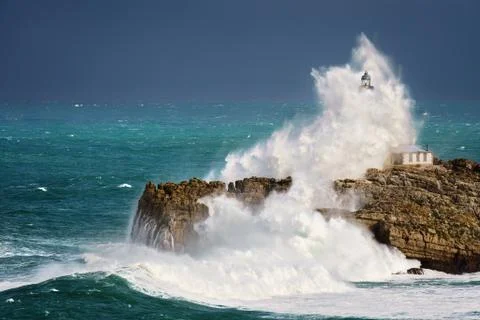 Wave splashing in Mouro lighthouse in Santander Stock Photos