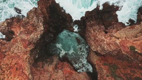 Wave streams into caves on wild coast shot by drone Stock Footage 203595822