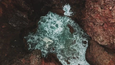Wave streams into caves on wild coast shot by drone Stock Footage 203597922