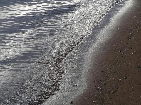 Wave with sun reflections at dusk Stock Photos