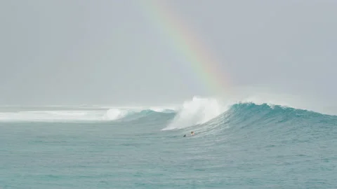 Wave travelling from the side with surfer in the front and rainbow in the ba Stock Footage 144029265