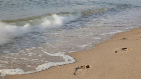 Wave washes away footprints in the sand Stock Footage 114993038